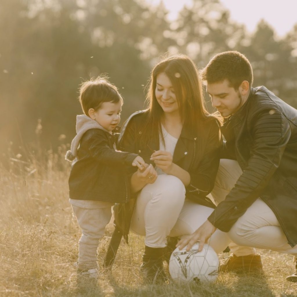 Husband and wife with son outside playing soccer.